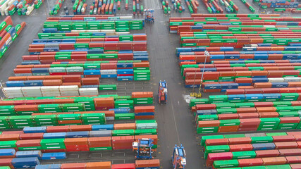 DRONE: Industrial forklifts carry shipping containers around the colorful port.