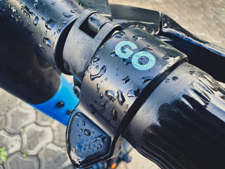 Close-up of a wet electric scooter handlebar with 'GO' text.