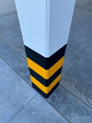 Spacious empty warehouse interior featuring white structural columns with black and yellow safety stripes, steel roof trusses, concrete floor, and open industrial architecture.
