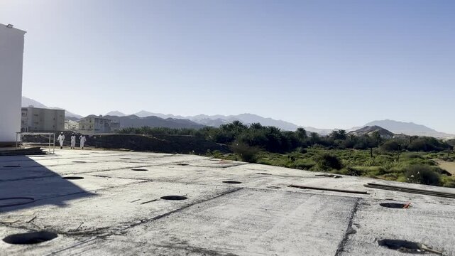 Cinematic view of the white facade and dome of Masjid Al-Areesh in Badr, a site of immense Islamic historical significance, set against a clear sky and desert mountains.