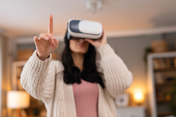 Young woman wearing a virtual reality headset at home and interacting with digital content. Lifestyle technology scene focused on innovation and immersive experience.
