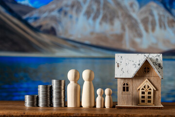 Wooden house toy model, stack of coins and figures of people on nature background. Concept of planning to save money for purchase or construction of a home, mortgage and real estate investment