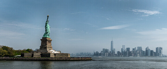 Statue of liberty overlooking new york city skyline on a sunny day