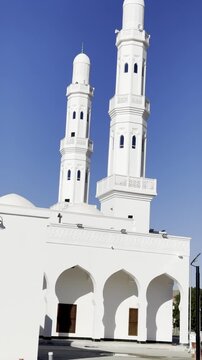 Exterior view of Masjid Areesh featuring white Islamic architecture with domes and minaret under a clear blue sky, a historic mosque associated with early Islamic heritage and spiritual significance.