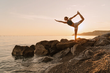 Woman practicing yoga at seaside at sunset or sunrise. Holistic Health and Mental Well-Being.