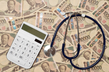 聴診器と電卓と敷き詰められた一万円札