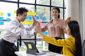 Obraz premium Diverse team celebrating a successful achievement with high-fives in office. Motivated colleagues express joy and teamwork.
