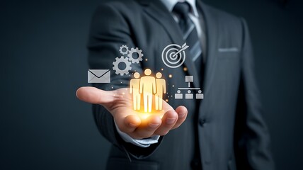 Strategic business management concept with a businessman holding digital icons for people, goals, gears, and communication.