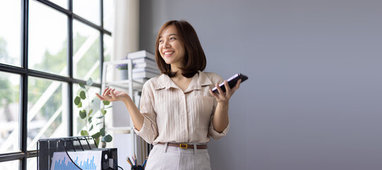 Young Asian businesswoman using a smartphone while glancing away in office.