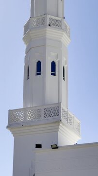 Bright daytime view of Masjid Areesh in Madinah, featuring its iconic white minaret, intricate Islamic architecture, and traditional geometric carvings set against a clear, sunny sky.