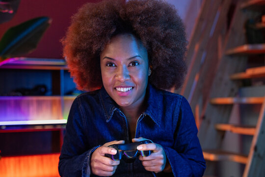 Cheerful female gamer holding a controller at home setup