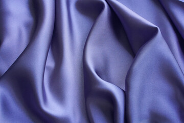 Violet silk fabric. The smooth, elegant texture of deep lilac silk or satin with soft longitudinal folds and violet hues can be used as a background for graphic design. Soft light and shadows.