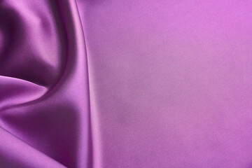 Pink silk fabric with soft folds and purple hues in the shadows on the side of the image and a smooth plain textured surface with copy space, for use as an elegant beautiful textile background.
