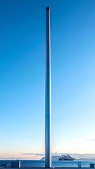 Tall Silver Pole Reaching into Blue Sky over Cityscape Horizon Daytime