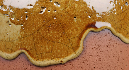 Close-up of a textured, cracked surface with glossy, dripping amber liquid and a reddish-brown, porous base