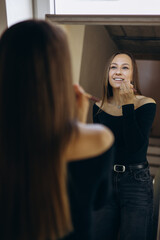 Young woman applying lip liner and looking into the mirror