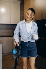 Woman vacuuming at home using rechargeable vacuum cleaner