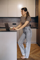 Woman drinking coffee and working on laptop from home
