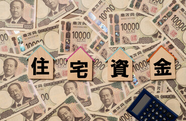 住宅資金の文字と家形のプレートと敷き詰められた一万円札