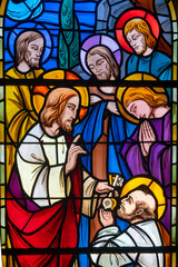 Stained glass of Jesus hands over the keys of the Church to Saint Peter the apostle.