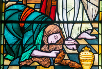 Stained glass of Saint Mary Magdalene washing the feet of Jesus Christ with perfume and her hair.