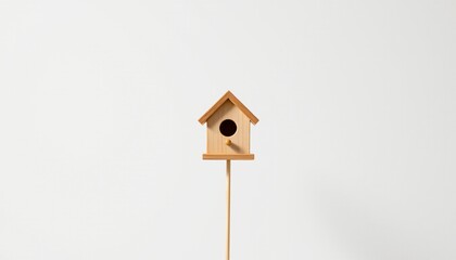 A small wooden birdhouse mounted on a pole against a neutral background.