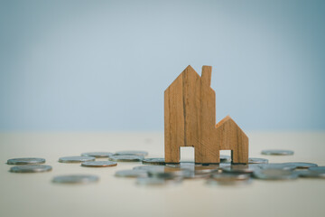 Wooden house model standing on coins, symbolizing real estate investment, property savings, mortgage planning, housing finance, home ownership, wealth growth and financial security.