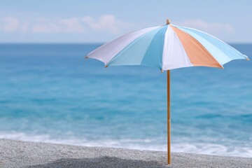 a beach umbrella with striped orange and blue colors on the sand by the sea, a summer vacation concept.
