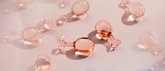 Skin care capsules face serum, revitalising capsule for youthful skin, collagen Professional cosmetics. Face care, pink liquid-filled capsules over beige. Beauty treatment. Top view, flat lay 