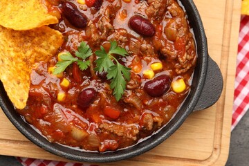 Delicious chili con carne with nachos on grey table, top view