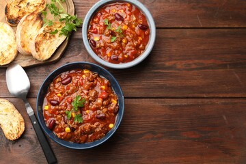 Fototapeta premium Delicious chili con carne served on wooden table, flat lay. Space for text