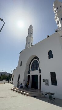 Daytime exterior view of Masjid Areesh showing white Islamic architecture, tall minaret, and worshippers at the mosque entrance, reflecting faith, community, and peaceful spiritual life.