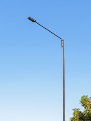 Modern street light against a bright blue sky providing illumination for urban safety and energy efficiency under natural light