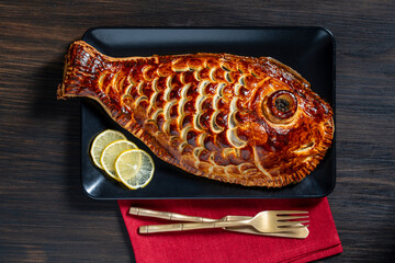 Baked dorado fish in yeast puff pastry, closeup, top view. Healthy food concept. Whole fish wrapped in dough and baked in the oven