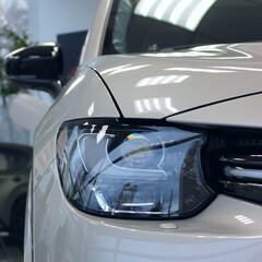 Headlight of white car in a dealership showroom close up view stock photo