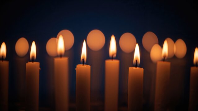 Seven candles with lit flames glowing in a dark background.