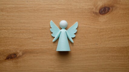 Fototapeta premium Wooden angel figure with wings and spherical head on a wooden surface. Spiritual and decorative symbol. Handmade craft. The concept of peace, spirituality, and craftsmanship.