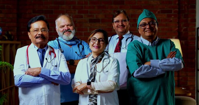 Indian confident doctors standing in group looking at camera portrait of senior surgeons and physicians with confident smiles wearing medical coats inside modern hospital healthcare ward