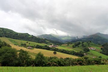 Obraz premium Countryside scenery with green fields and traditional houses on the Camino route outside Saint-Jean-Pied-de-Port, photographed in July 2024.