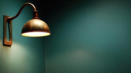 Obraz premium Rusty brass wall lamp with a curved arm casts warm light onto a teal wall. Concept Rusty brass wall lamp, warm ambient light, teal wall, curved arm, industrial decor