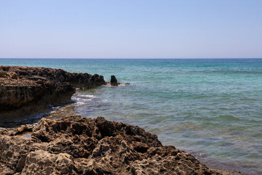A beach with a rocky shore and clear turquoise water - Powered by Adobe