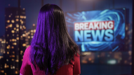 Female news presenter gestures confidently in modern studio, vibrant lighting, breaking news screen behind, professional broadcast, journalism, television media, live reporting studio background