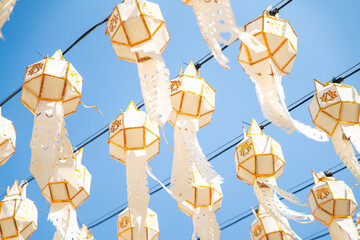 Traditional White Lanna Lanterns Hanging Against Blue Sky in Northern Thailand Temple