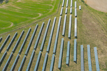 Farma paneli fotowoltaicznych na zielonej łące. Jest słoneczny dzień. Zdjęcie z drona.