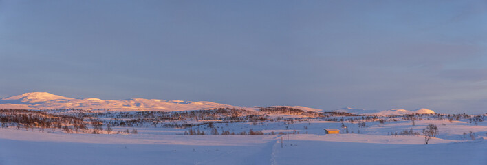 The evening sun shining over a snow-covered mountain range