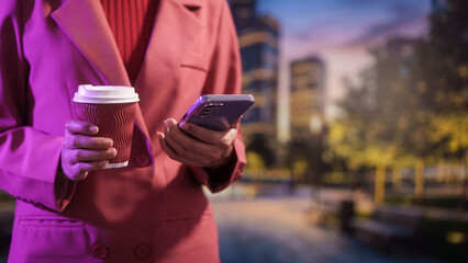 Business professional holding takeaway coffee and smartphone outdoors, modern city background, evening light urban lifestyle, mobile communication productivity work break,life balance.