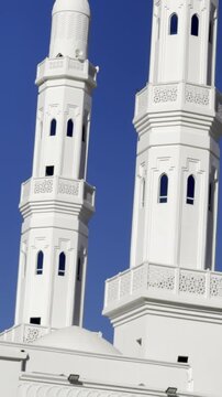 A crisp architectural shot of Masjid Al-Areesh (the White Mosque) in Badr, Saudi Arabia, featuring two elegant white minarets rising against a clear blue sky&mdash;ideal for Islamic heritage projects.
