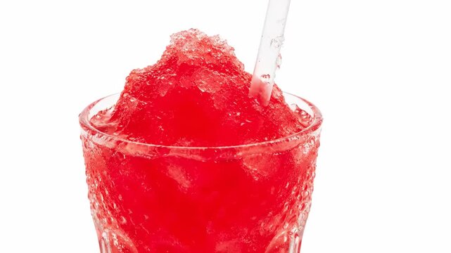Red Slush Drink with Straw - This is a close-up video of a red slush drink in a clear glass with a straw. The drink is overflowing slightly and the glass is covered in condensation.