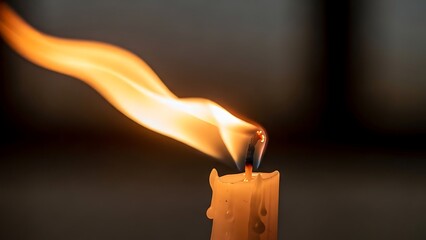 Warm candle flame burning brightly in darkness