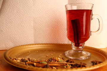 Warm drink in a glass cup with spices on a tray during a kitchen setting in the afternoon